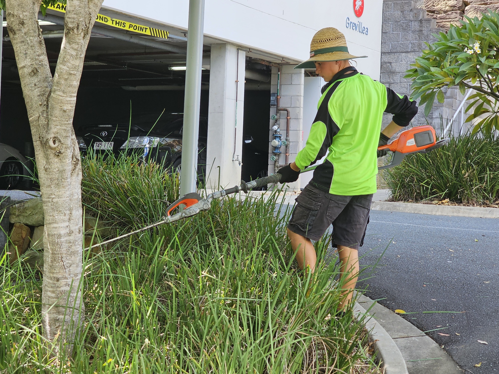 Keaan carefully maintaining a garden bed with a battery-powered trimmer
