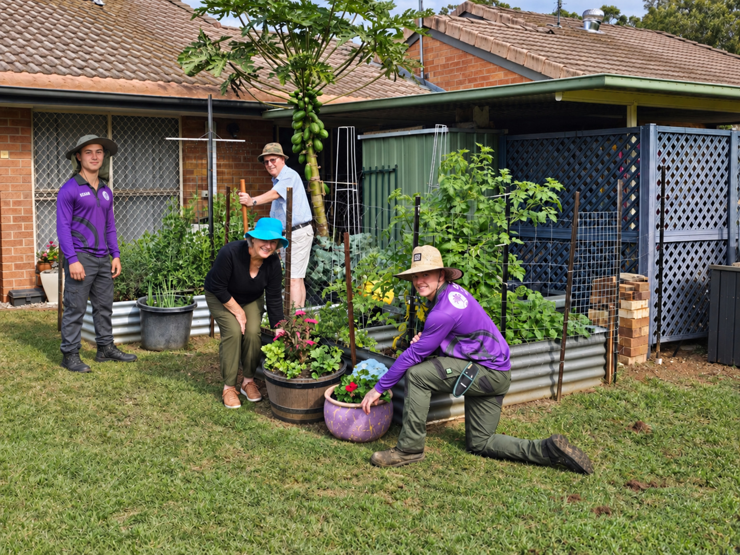 Two Excel team members and two residents enjoying their shared vegetable garden