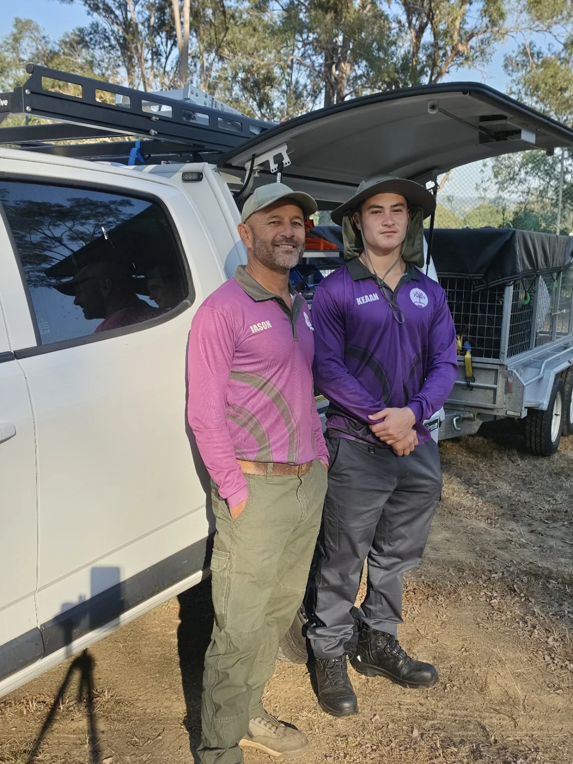Jason and Keaan in Excel uniforms beside the work ute and trailer